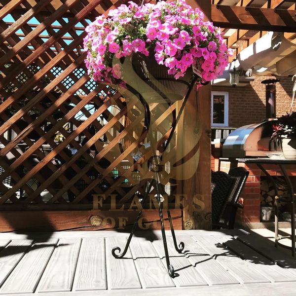 Flower pot with pink flowers on a metal stand.