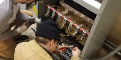 Apprentices learning how to install a transformer