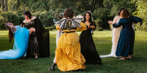 People in elaborate costumes dance outdoors on grass.