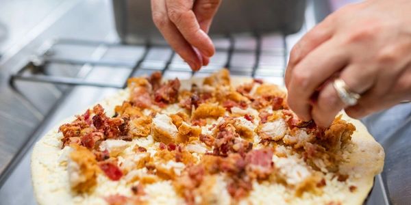A man spreading chicken at the pizza