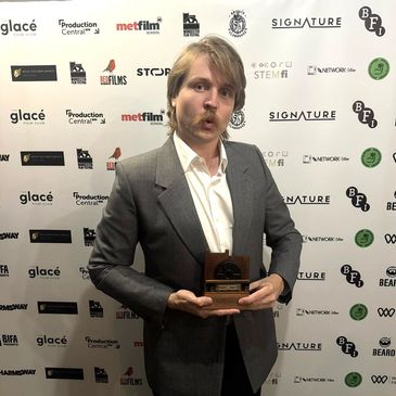 Man in suit holding an award with surprised expression.