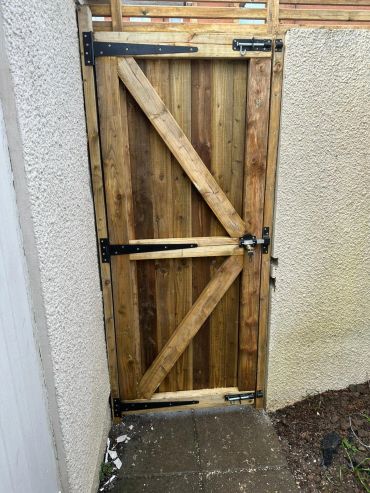 Wooden garden gate with locks between two walls.
