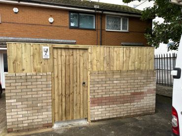 New wooden fence and gate with brick base in front of a house.