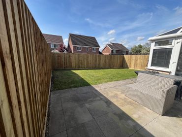 Sunny backyard with wooden fence and patio furniture.