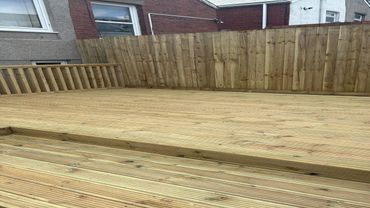 Newly built wooden deck with a privacy fence in a backyard.