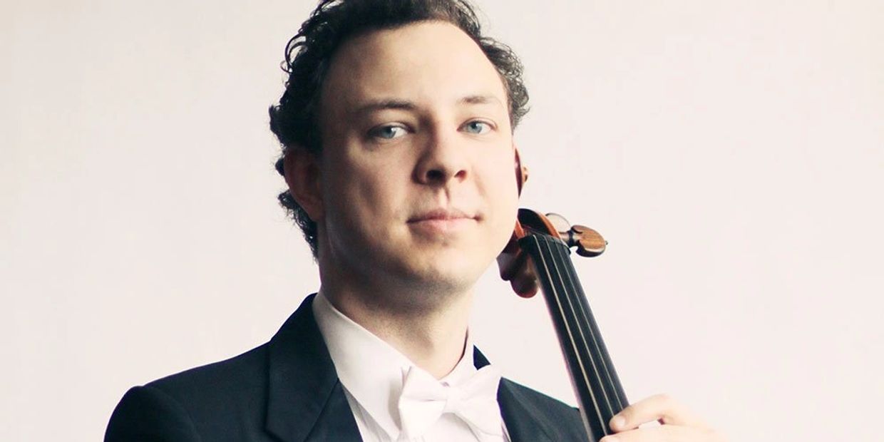 Man in formal attire holding a cello close to his face.