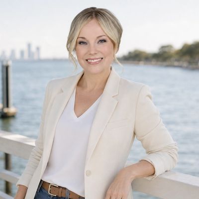 Smiling woman in light blazer standing by waterfront.