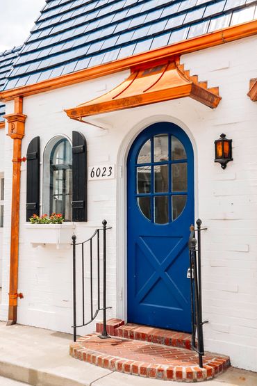 White brick house with a blue door and orange accents.