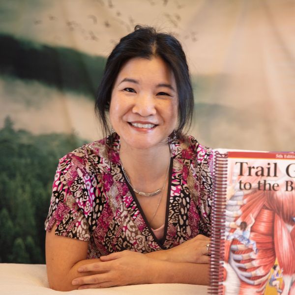 Bonnie Chan license massage therapist in Westminster, Colorado poses with Trail Guide to the Body.