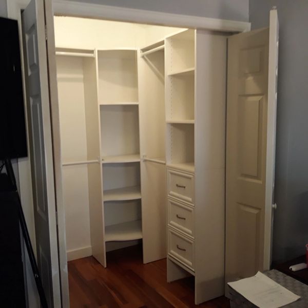 Empty walk-in closet with white shelves and wooden floor.