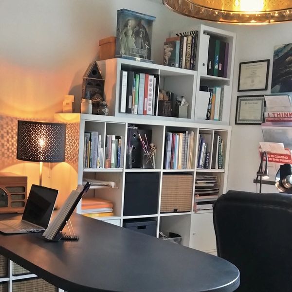 Cozy home office with organized shelves, a desk, and soft lighting.