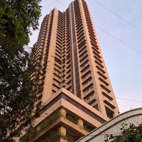Tall residential building seen from below with some greenery.