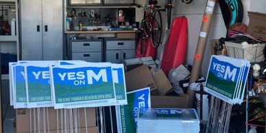 Political signs supporting Measure M in a garage.