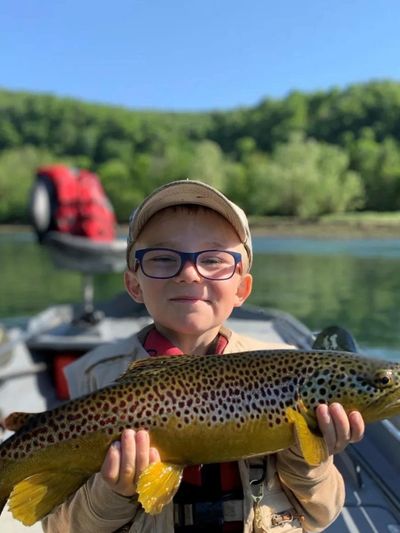 an image showing a kid holding a trout representing unforgettable fly fishing experience