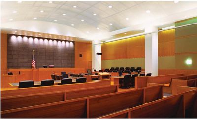 Empty courtroom with wooden benches and judge's bench.