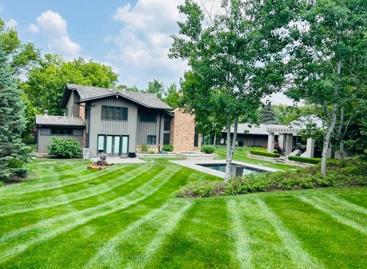 Well-maintained backyard with a lawn mower, pool, and modern house.