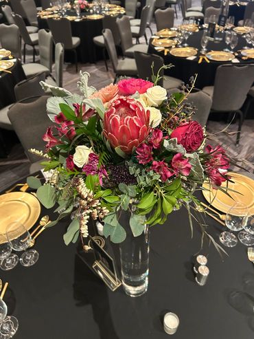 Elegant floral centerpiece on a banquet table with gold-rimmed plates and glassware.