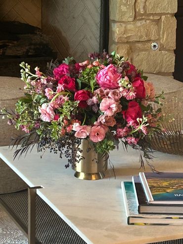 Elegant bouquet of pink and red flowers in a brass vase on a marble table.