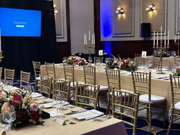 Elegant banquet setup with gold chairs and floral centerpieces.