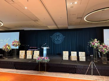 Elegant stage setup with floral arrangements and decorated love boxes for a formal event.