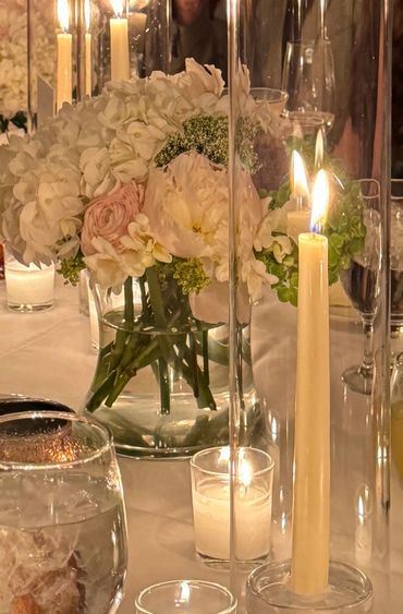 Elegant table setting with white flowers and lit candles creating a warm ambiance.