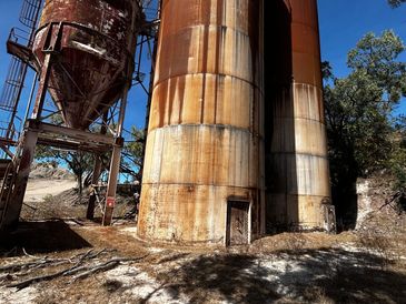 Rusty industrial silos under clear blue sky.