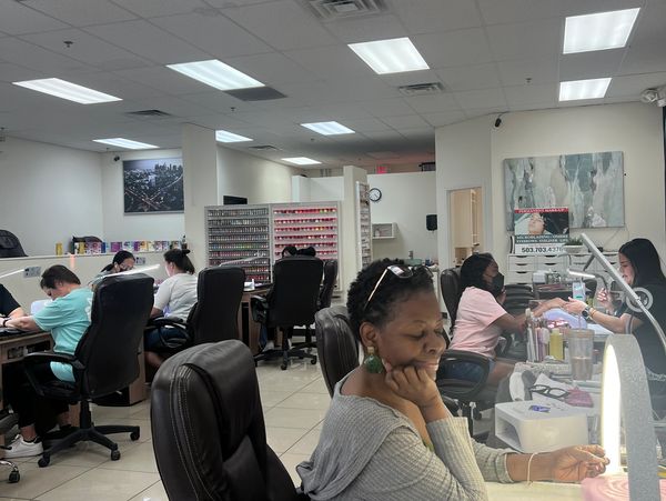 People getting manicures in a spacious nail salon with bright lighting.