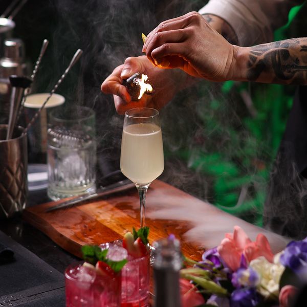 Bartender lighting a citrus peel on fire over a cocktail. frmefest photographer and content creator festival at carriage works in Sydney.