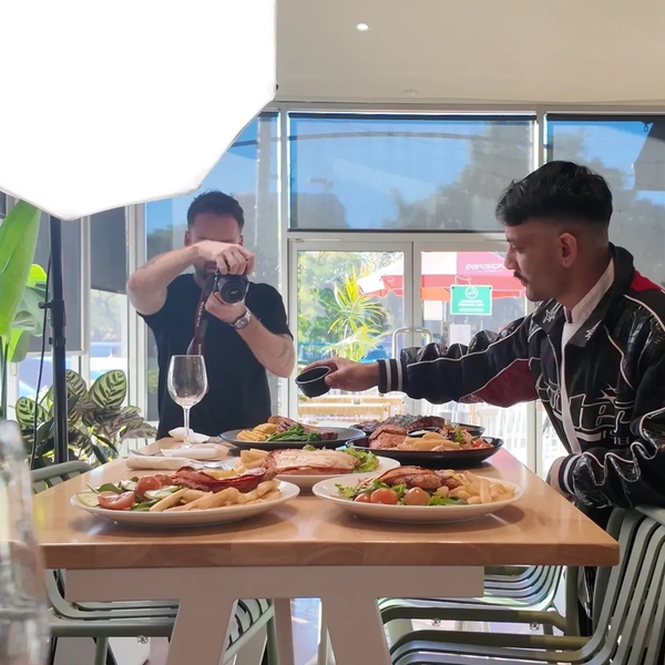 Man pouring sauce on food while being photographed. food photography session at the pineapple hotel woolloongabba brisbane.