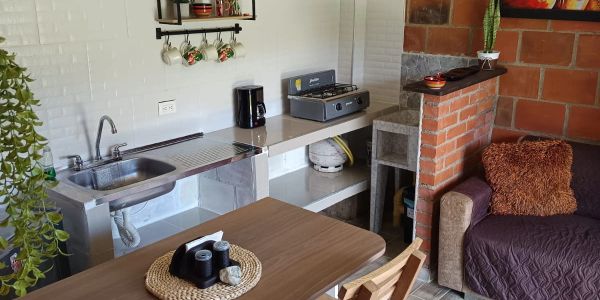 Cozy kitchen and living area with stainless steel counters and a small sofa.