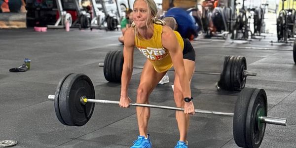 Woman lifting a heavy barbell in a gym.