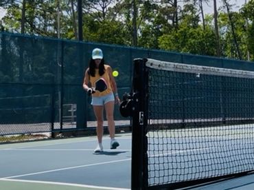 Person playing pickleball on an outdoor court during daytime.