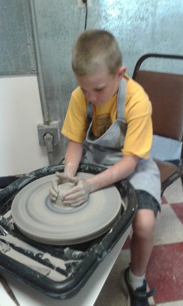 kid throwing pottery on the wheel