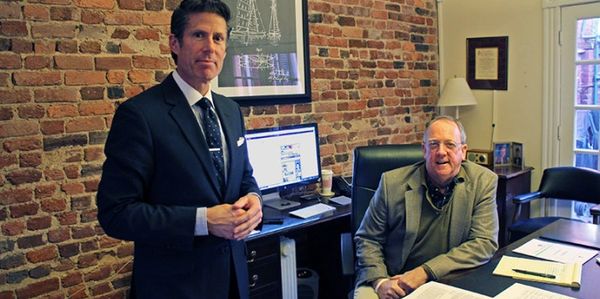 Two men in an office with brick walls.