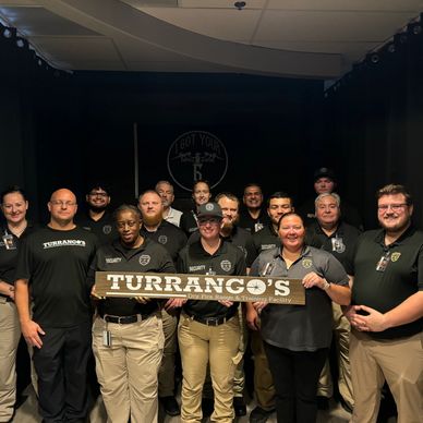 Group of security team members holding a Turrango's sign inside a training facility.