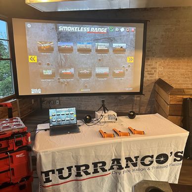 Training setup for dry fire shooting with a laptop, projector, and laser guns on a Turrango's table.