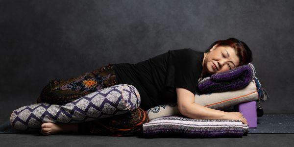 Woman resting on a stack of cushions with eyes closed.