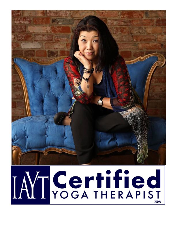 Woman sitting on blue couch with IAYT Certified Yoga Therapist logo.