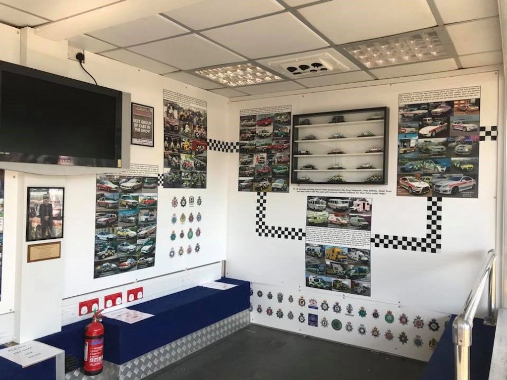 A room with racing-themed posters, model cars, and blue benches.