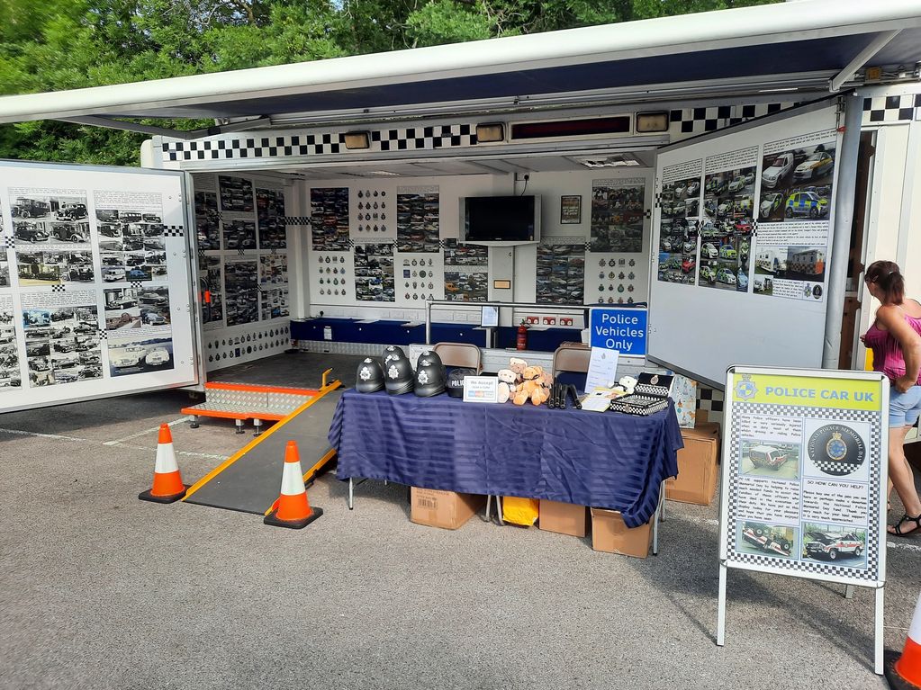 An informative police vehicle display booth with helmets, teddy bears, and posters.