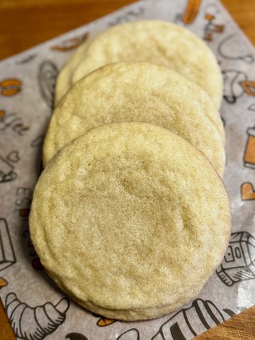 Three plain sugar cookies stacked on decorative paper.