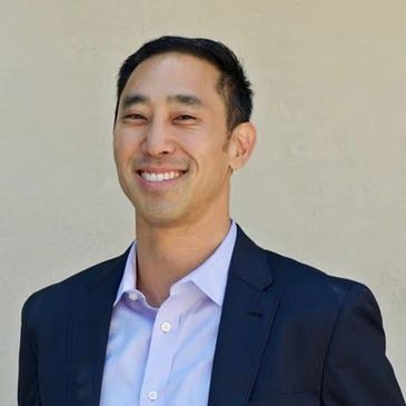 Man in suit smiling against a plain background