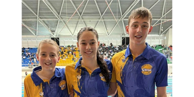 Three swimmers in Griffith Swim Club uniforms pose at a poolside event.