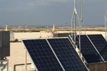 Solar panels installed in a desert-like industrial area.