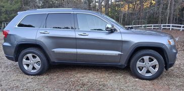 Side view of a gray Jeep Grand Cherokee parked outdoors.