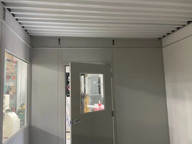 Interior view of a Modular Office featuring a door and window with gray paneling & roof-deck on top.