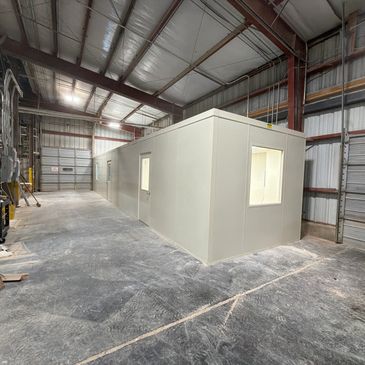 A newly constructed modular office building inside an industrial setting, with several windows, door