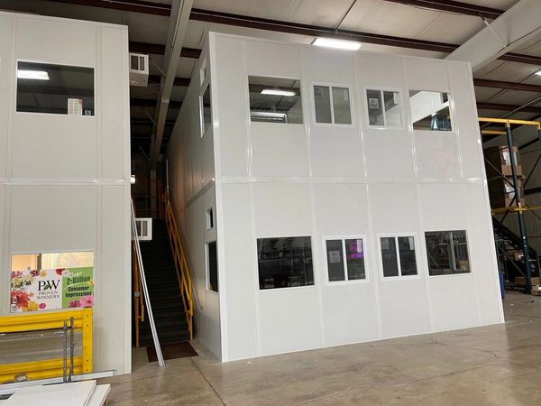 A new white two story modular office with several windows and sliding glasses with a set of stairs i