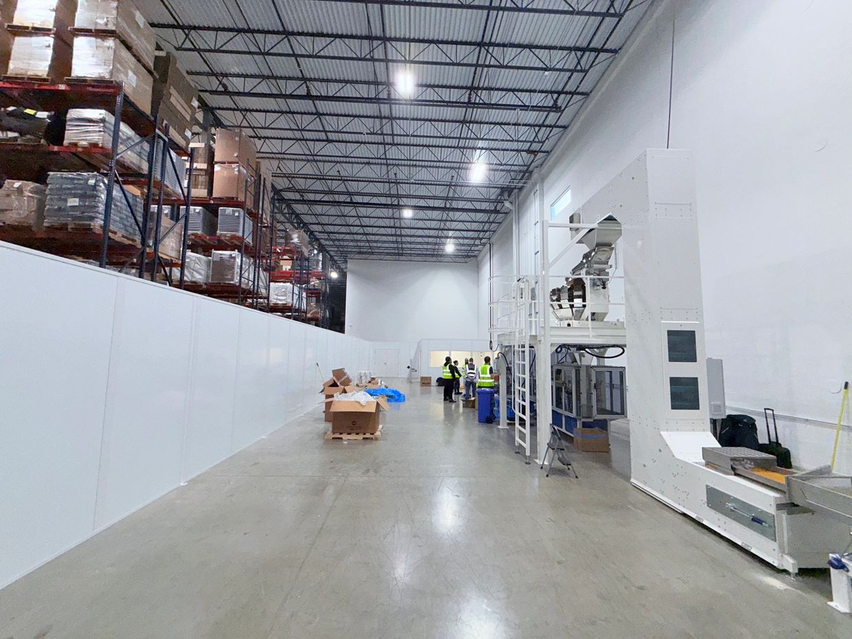 A white free standing prefab wall partition attached to a modular office inside a warehouse setting
