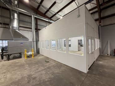 A modular tall wall building with windows, situated in an industrial environment. By SoFlo Installat